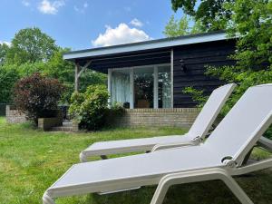 two white lounge chairs in front of a cabin at Bungalow Zandzegge | 4 personen - Vakantiepark De Kremmer in Gasselte