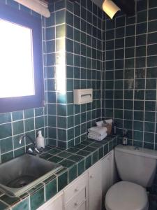 Un baño con azulejos azules, lavabo e inodoro. en Apartment du Pic de l 'Ours, en Théoule-sur-Mer