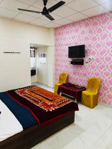 a bedroom with a bed and two yellow chairs at Hotel Tathastu in Rāmtek