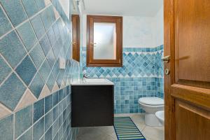 een blauw betegelde badkamer met een toilet en een spiegel bij Villetta Lu Lioni in San Teodoro