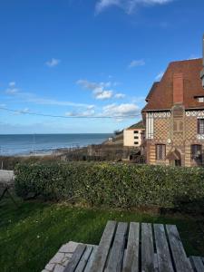 a wooden bench in front of a house and the ocean at Les Villas de Puys - Dieppe in Dieppe