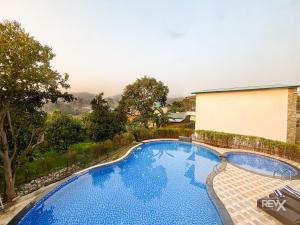 a swimming pool with a view of a house at Wonderwood Corbett Resort -1min walk to River with Deep Jungle Trail in Rāmnagar