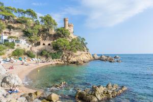 une plage avec des gens et un château au loin dans l'établissement 2Pon01 - Lloret de Mar, à Lloret de Mar