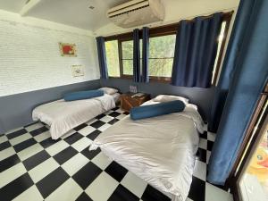 two beds in a room with a checkered floor at บ้านเชิงเขา โฮมสเตย์ in Ban Mai