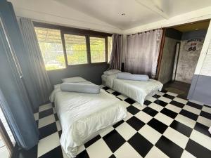 two beds in a room with a checkered floor at บ้านเชิงเขา โฮมสเตย์ in Ban Mai