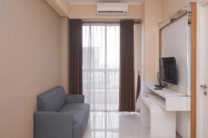 a living room with a blue chair and a television at Comfortable and Homey 1BR Apartment at Silkwood Residences By Travelio in Tangerang