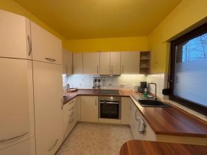 a kitchen with white cabinets and a yellow ceiling at Ferienhaus Usedom - Haus Andrea - 300Meter zur Ostsee in Ostseebad Koserow