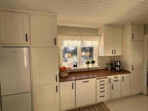a kitchen with white cabinets and a window at Hus Hornsö in Blomstermåla