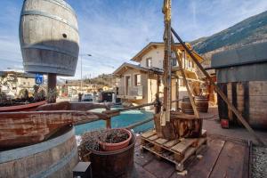 a wooden deck with a watermill and a house at Antirouille Casa Vacanze in Aymavilles