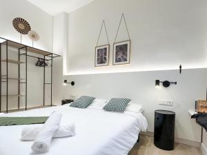 ein weißes Schlafzimmer mit zwei Betten und zwei Bildern an der Wand in der Unterkunft Apartment Gaudi in Vilanova i la Geltrú