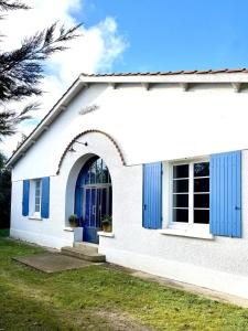 una casa blanca con una puerta azul en Villa MICHITA proche plage by E&A, en Grand-Village-Plage