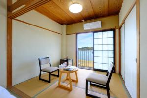 a room with two chairs and a table and a window at 鹿鳴館 in Yurihama