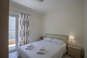 a white bedroom with a bed with towels on it at Darina central Accommodation in Pefkochori