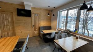 a restaurant with wooden tables and chairs and a window at Nad Prutom in Vorokhta