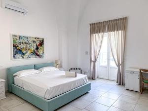 a white bedroom with a blue bed and a table at Dallatorre B&B in Lizzano