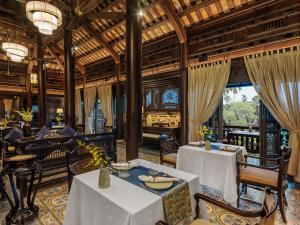 フエにあるAncient Huế Garden Housesのテーブルと椅子と窓のあるダイニングルーム