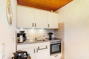 una cucina con mobili bianchi e un lavandino di KleineMuschelbude a Dornum