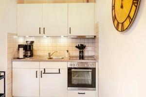 una cucina con mobili bianchi e un orologio sul muro di KleineMuschelbude a Dornum Altre 13 foto