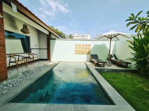a swimming pool next to a house with an umbrella at Sejati Villas - Petitenget in Seminyak