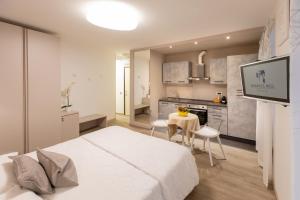 a bedroom with a white bed and a kitchen at Residence Arco in Trieste