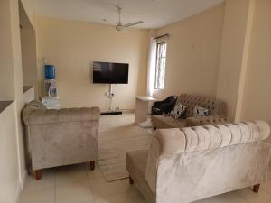 Una sala de estar con dos sofás y un televisor de pantalla plana. en SHE Homes, en Mombasa