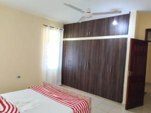 1 dormitorio con armario grande de madera y cama en SHE Homes, en Mombasa 2 fotos más