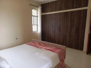 Un dormitorio con una gran cama blanca y armarios de madera. en SHE Homes, en Mombasa