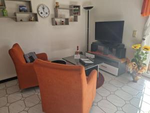 un salon avec deux fauteuils et une télévision dans l'établissement Ferienwohnung Pentagono, à Engelskirchen