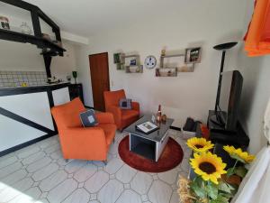 - un salon avec deux chaises orange et une télévision dans l'établissement Ferienwohnung Pentagono, à Engelskirchen