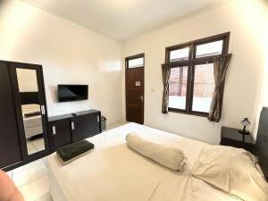 a bedroom with a large white bed and a window at Paradise Inn in Legian +9 photos