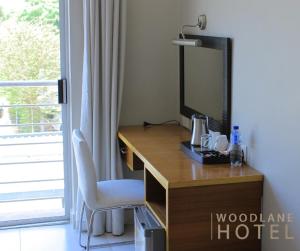 a desk with a television and a chair in a room at Woodlane Hotel in Gaborone +1 photo