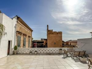 a patio with chairs and a building in the background at Dallatorre B&B in Lizzano