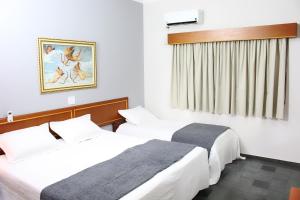 a hotel room with two beds and a window at ARQ Inn Hotel in Ribeirão Preto