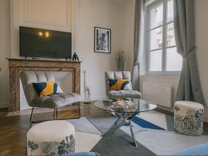 a living room with two chairs and a table and a television at Appartement refait à neuf avec cachet de l'ancien in Saumur +9 photos