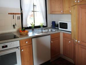 eine Küche mit Holzschränken, einer Spüle und einem Geschirrspüler in der Unterkunft Ferienhaus Nr 41, Typ C, Feriendorf Hochbergle, Allgäu in Bichel