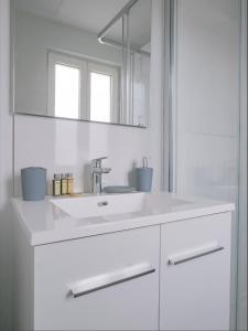 a white bathroom with a sink and a mirror at Appartement refait à neuf avec cachet de l'ancien in Saumur