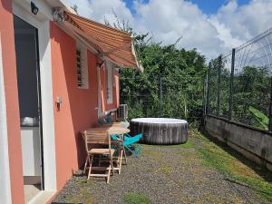 a house with a table and chairs and a barrel at Appartement Bleu Corail avec Jacuzzi in Les Trois-Îlets
