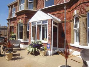 een bakstenen gebouw met een veranda met stoelen en bloemen bij Brooke House in Shanklin