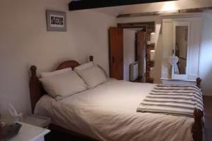 a bedroom with a bed with white sheets and pillows at Characterful Cottage Daisy Lodge in Thornage