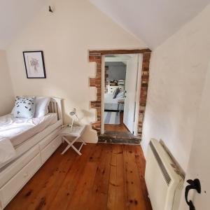 une chambre blanche avec un lit et un miroir dans l'établissement Characterful Cottage Daisy Lodge, à Thornage