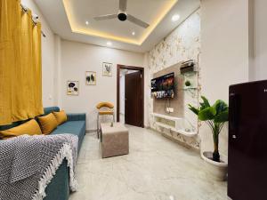 a living room with a blue couch and a tv at Home Escape Cozy 1BHK Apartment Mahalaxmi Nagar in Indore