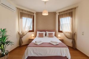una camera con un grande letto e due finestre di Sunstone Serenity Villa a Città di Corfù Altre 30 foto