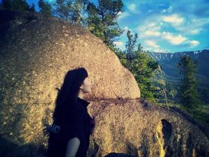 una mujer sentada sobre una gran roca en Qoitas, en Berëzovka