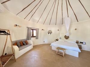 a white bedroom with a bed and a couch at Maison Fimela - Boutique Hotel in Fimela