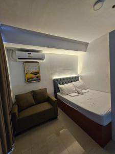 ein kleines Schlafzimmer mit einem Bett und einer Couch in der Unterkunft 1802 West Jones Residences in Cebu City + 25 Fotos