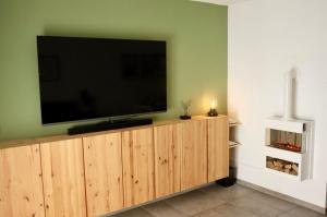 a flat screen tv sitting on top of a wooden entertainment center at Ferienhaus Nr 47, Kategorie Premium, Feriendorf Hochbergle, Allgäu in Lechbruck