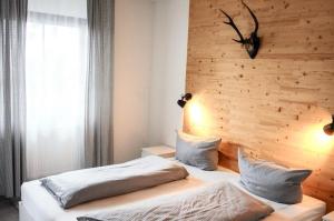 two beds in a bedroom with a wooden wall at Ferienhaus Nr 47, Kategorie Premium, Feriendorf Hochbergle, Allgäu in Lechbruck