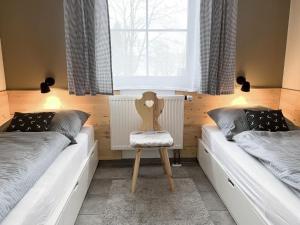 a bedroom with two beds and a chair in it at Ferienhaus Nr 47, Kategorie Premium, Feriendorf Hochbergle, Allgäu in Lechbruck +12 photos