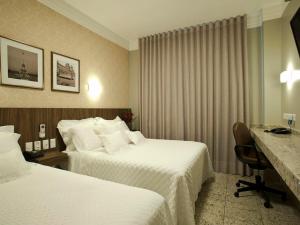 Habitación de hotel con 2 camas y escritorio en Nohotel Premium Americana, en Americana