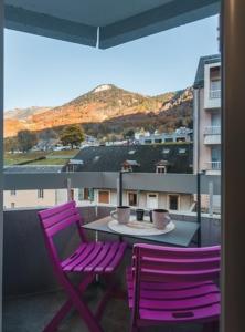2 lila Stühle und ein Tisch auf dem Balkon in der Unterkunft Studio 4 personnes pied télécabine Petit Vignemale in Cauterets